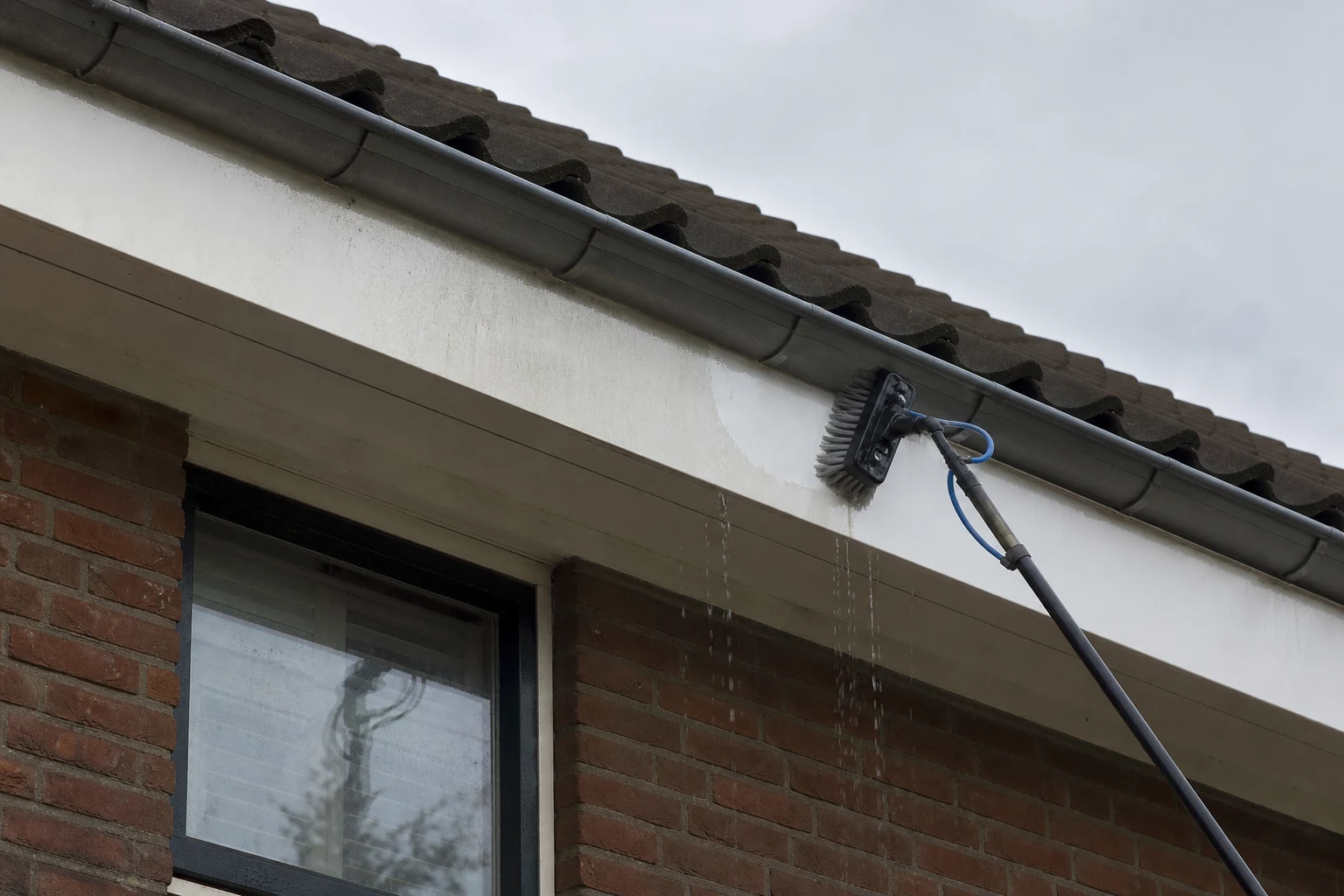 Watergevoede borstel reinigt het witte boeideel van een Nederlandse woning